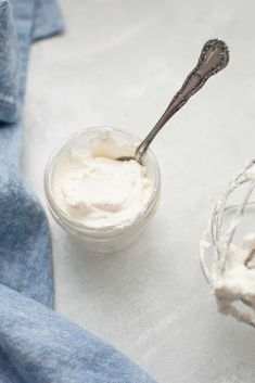 a spoon in a small glass bowl filled with whipped cream next to a blue towel