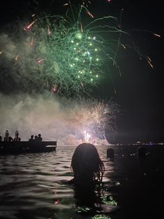 people are in the water watching fireworks go off