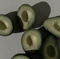 an avocado cut in half on a white surface