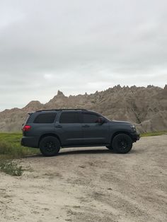 a gray suv parked on the side of a dirt road