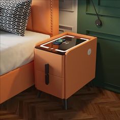 an orange nightstand with a phone on it next to a bed