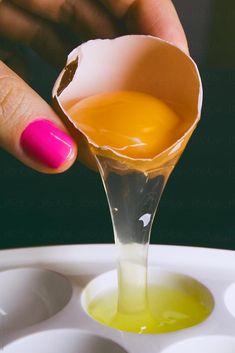 a person holding an egg in a cup with liquid coming out of it and another hand reaching for one