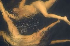 a woman is floating in the water with her arms spread out and legs bent forward