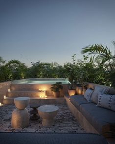 an outdoor living area with couches, tables and candles lit up at night time