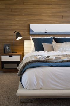 a bedroom with a large bed and wooden headboard in front of an ocean view