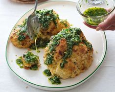 someone is dipping sauce onto some food on a white plate with green trimmings