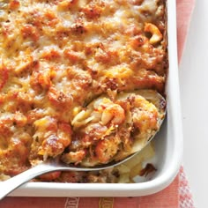 a casserole dish with meat and cheese in it on a pink napkin next to a fork