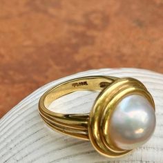 New, but old pieces, never worn, recently acquired from a premiere jeweler located in Minneapolis, MN for many years- a rare opportunity. 18KT yellow gold genuine, double bezel, round, mabe pearl ring Size 6.50 Sizable by us for a fee or your local jeweler Weight: 12.2 grams Band width: 3mm in back 11.50~12mm round mabe pearl Stamped 18k Double Bezel Ring, Luxury Pearl Ring With Bezel Setting, Timeless Gold Dome Ring With Cabochon, Mabe Pearl Rings, Classic Domed Collectible Jewelry, Classic Dome Ring With Gemstone, Classic Gemstone Dome Ring, Classic Yellow Gold Rings With High Luster, Timeless Gold Rings With High Luster