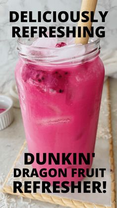 a pink drink in a mason jar with a wooden straw sticking out of it and the text deliciously refreshing dunkin'dragon fruit refresher