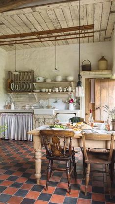 an old fashioned kitchen with tile flooring and exposed beams on the ceiling is shown