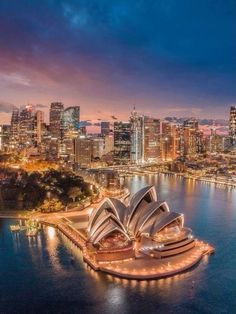 an aerial view of the sydney opera house and city skyline at night, with lights on