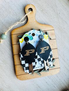 two black and white keychains are sitting on a wooden board next to some beads