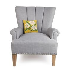 a gray chair with a yellow pillow on it's back and white flowers in the center