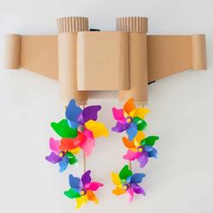 three colorful pinwheels are attached to a brown paper holder on a white wall