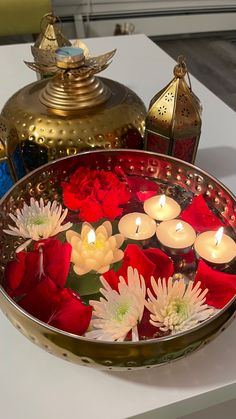 candles are floating in a bowl with red and white flowers