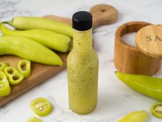 green peppers and jalapenos sitting on a counter next to a bottle of sauce