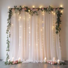 a wedding backdrop with candles and flowers on the floor in front of curtains that have lights