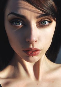 a close up of a woman's face with blue eyes and nose piercings