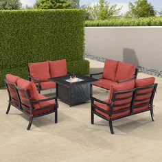 an outdoor patio furniture set with red cushions and black fire pit table on concrete flooring