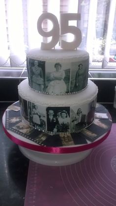 a three tiered cake with pictures on the top and numbers on the bottom, sitting in front of a window