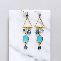 Our "chandies" are a modern take on classic chandelier earrings, using gemstone color combos and different stone shapes and sizes. - Bezel set blue chalcedony gemstones with iolite, blue chalcedony and london blue quartz- 3" long- French hooks- 14k gold plated .925 fine Italian sterling silver- Made in the USA in our NYC studio- Packaged in a gift box- Free shipping on US ordersHandmade to last. Our unique gold plating technique makes our jewelry tarnish resistant. The nature of natural gemstone Gemstone Chandelier, Ruby Quartz, Stones Earrings, Gold Chandelier Earrings, Classic Chandelier, French Hook Earrings, Chalcedony Stone, Gemstone Jewelry Handmade, Blue Quartz