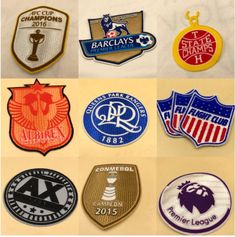 several different types of badges and emblems on a white surface, including one for each team