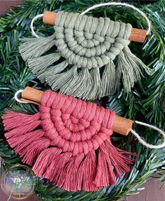 three different colored tassels are hanging from a wreath with pine needles and twine