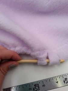 a person is measuring the length of a blanket with a wooden stick in their hand