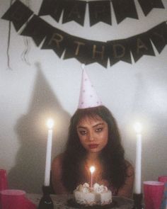 a woman sitting in front of a birthday cake with candles