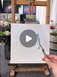 a person holding a paintbrush in front of an easel