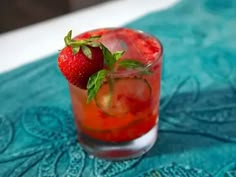 two strawberries on top of a drink in a glass with ice and garnish