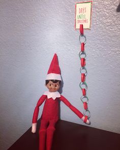 an elf with glasses and a sign hanging on the wall next to a chain that says days until christmas