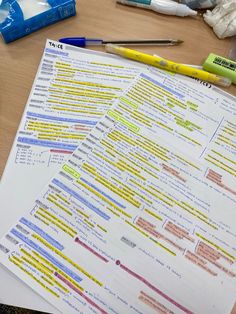 two sheets of paper sitting on top of a wooden table next to markers and pens