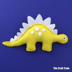 a yellow dinosaur brooch with white spots on it's head and tail, sitting on a blue background