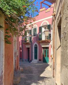 an alley way with pink buildings and green shutters