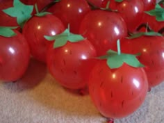 a bunch of red tomatoes with green leaves on them sitting on the floor next to each other