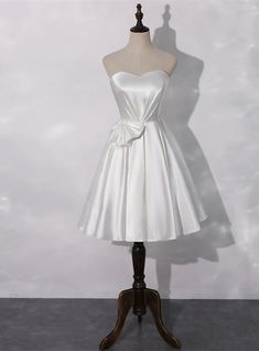 A-Line White Satin Sweetheart Pleats Homecoming Dress White Satin Evening Corset, White A-line Mini Dress For Evening, White Satin Mini Dress With Sweetheart Neckline, White A-line Mini Dress With Boned Bodice, Homecoming Dresses Knee Length, White A-line Mini Dress With Bow, Sweetheart Homecoming Dress, Red Ball Gown, Short Sleeve Wedding Dress