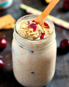 a jar filled with oatmeal sitting on top of a table next to cherries