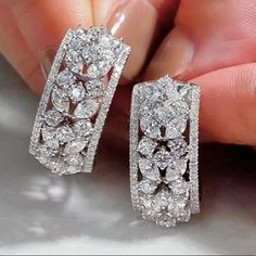 a pair of diamond earrings in the palm of someone's hand with their fingers