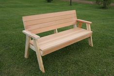 a wooden bench sitting on top of a lush green grass covered park field with trees in the background