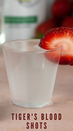 a close up of a strawberries in a glass on a table with the words tiger's blood shots