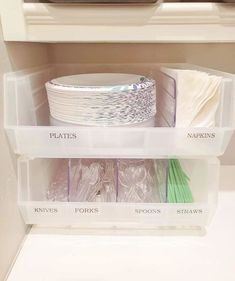 plastic storage bins filled with various items in a kitchen cabinet, labeled plates, napkins and spoons