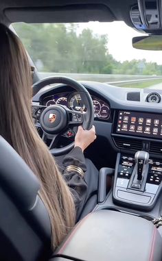 a woman driving a porsche car on the road