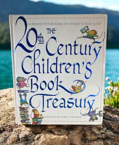 the 20th century children's book treasures is displayed on a rock next to water