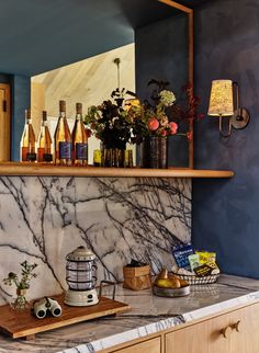 a marble counter top in a kitchen next to a wooden shelf with bottles on it