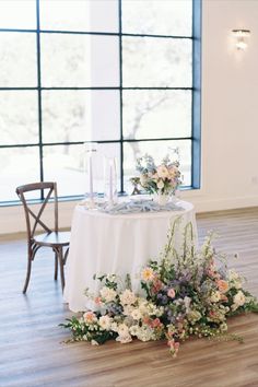 a table with flowers and candles on it in front of a large window at a wedding reception