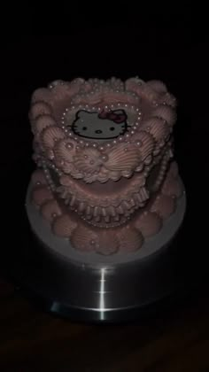 a hello kitty cake with pink icing and pearls on the top is sitting on a silver plate