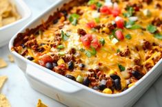 a white casserole dish filled with taco meat, cheese and black beans