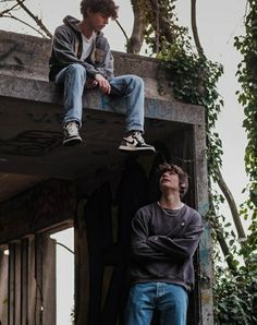 two young men sitting on top of a building