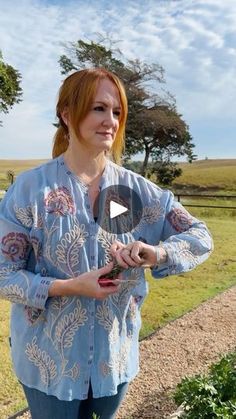 a woman standing in front of a field holding a knife